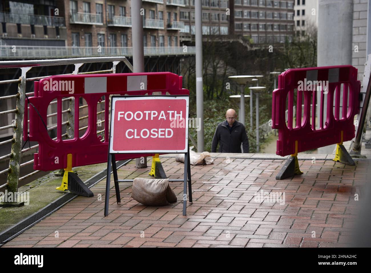 Salford, Großbritannien, 15. Februar 2022. Ein Teil einer Mauer am Flussufer ist in den Fluss Irwell in der Nähe der Blackfriars Bridge in Salford, Großbritannien, eingestürzt. Auf dem Fußweg über dem Einsturz wurden Schranken aufgestellt, aber einige Menschen ignorieren die Schliessung und benutzen den Fußweg trotz des Sicherheitsrisikos immer noch. Kredit: Terry Waller/Alamy Live News Stockfoto