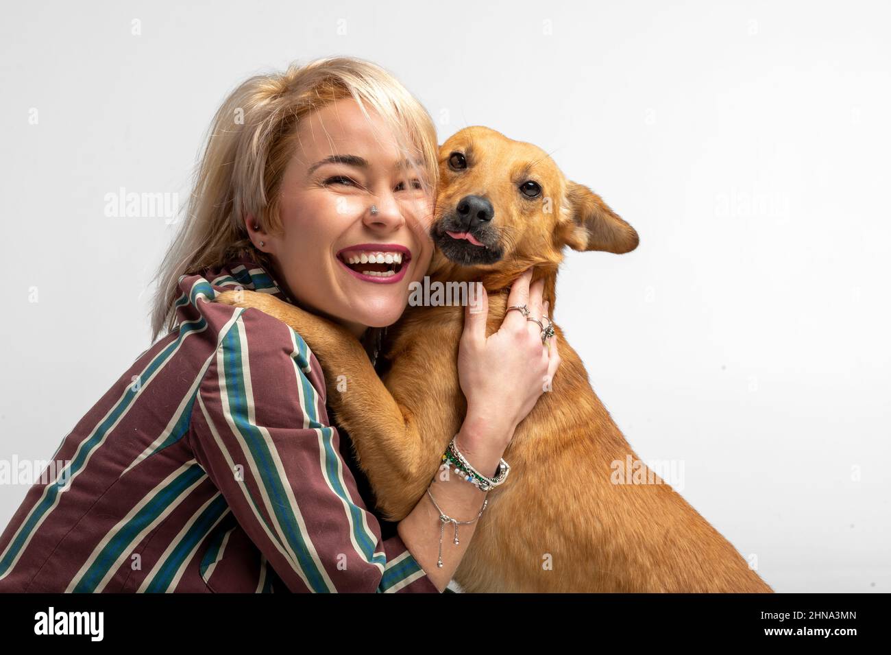 Eine niedliche junge Frau küsst und umarmt ihren Mischlingshund. Liebe zwischen Besitzer und Hund. Isoliert auf weißem Hintergrund. Studio-Porträt. Mädchen umarmt neue schöne Stockfoto