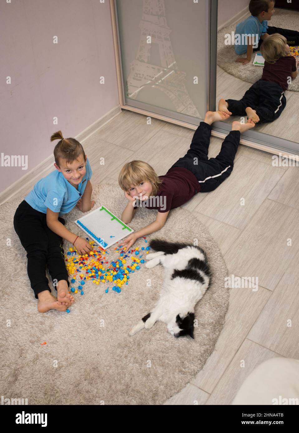 2 Barfußjungen Vorschulkinder spielen mit Spielzeugmosaik auf dem Boden des Kinderzimmers. Pädagogische Spiele, täglich interessante Aktivitäten für Kinder Stockfoto