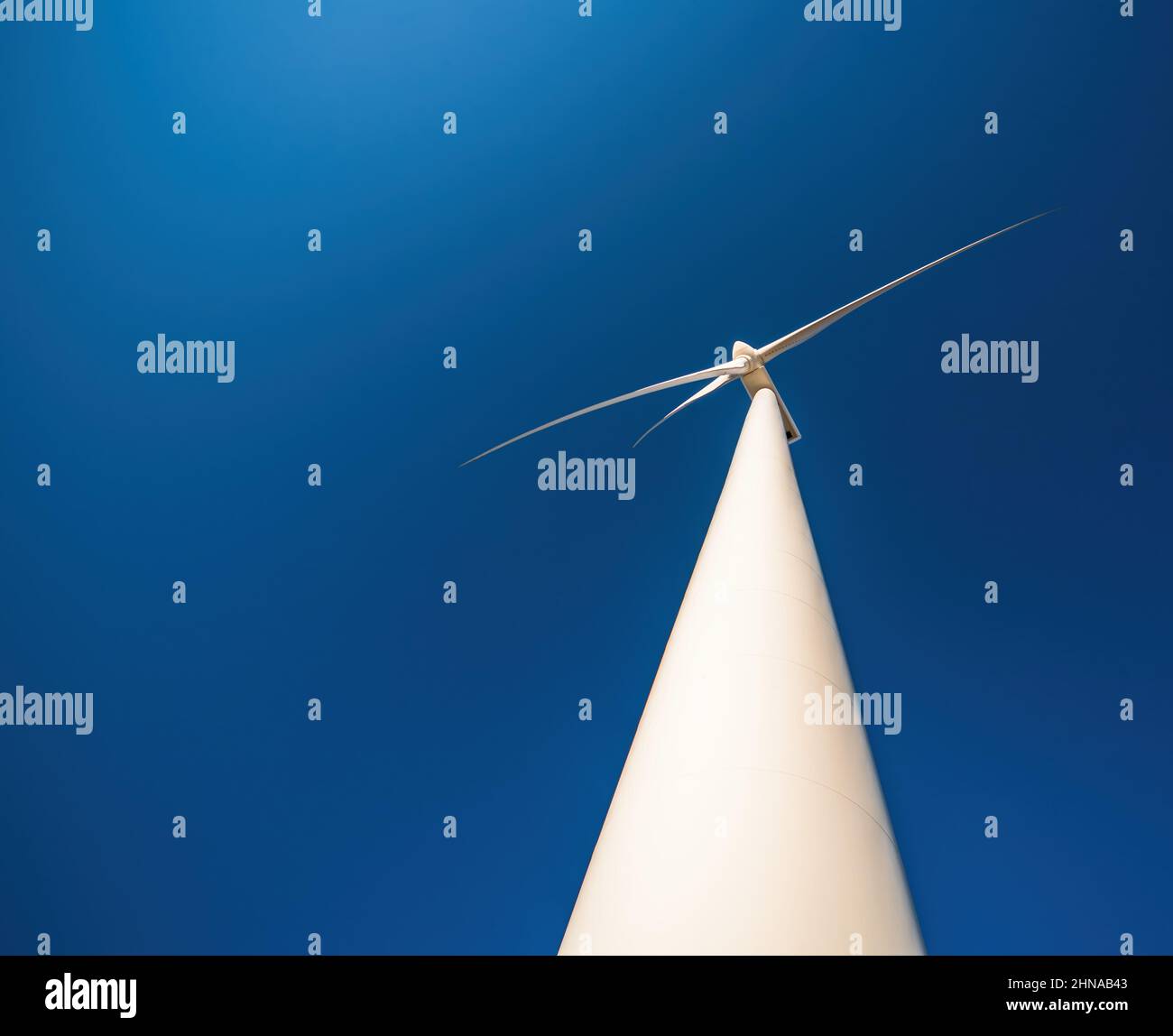 Nahaufnahme der Windenergieanlage gegen den blauen Himmel. Platz zum Kopieren, dramatische Ansicht von unten Stockfoto