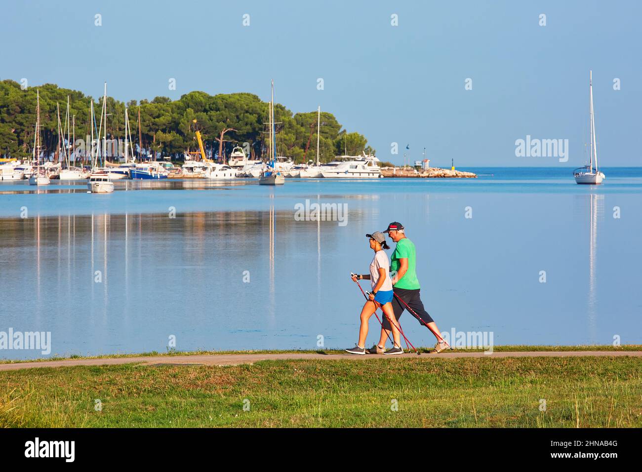 POREC, KROATIEN - 10th. August 2019: Reife Menschen genießen es, an einem schönen Sommermorgen skandinavisch am Meer entlang zu spazieren. Stockfoto