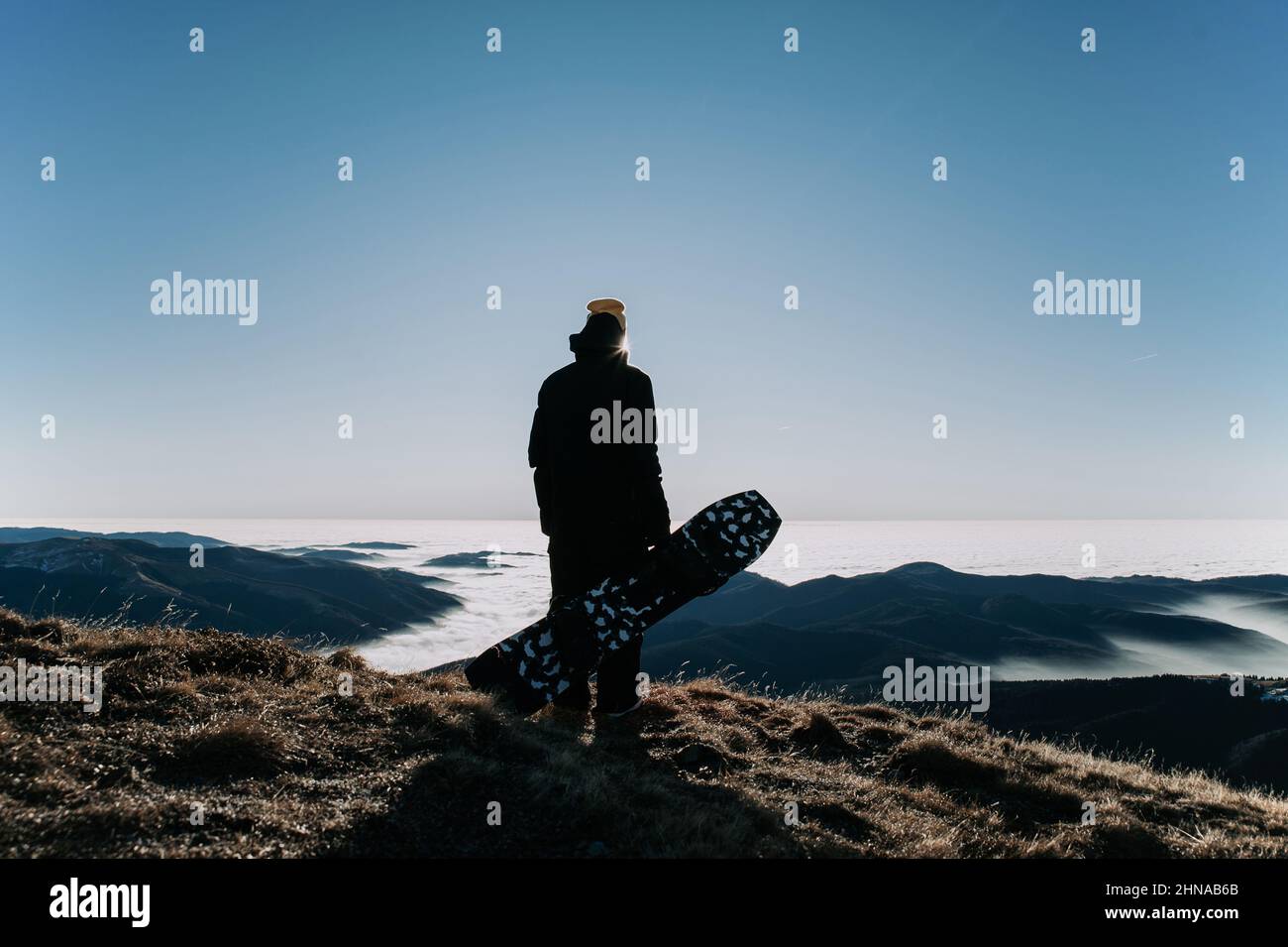 Silhouette eines Snowboarders, der sein Snowboard am Berg hält Stockfoto