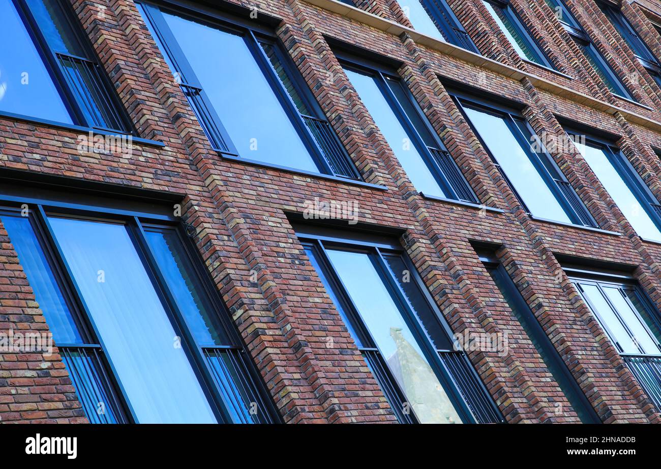 Schräge Aussicht auf die moderne rote Ziegelsteinfassade mit blauen Glasfenstern - Maastricht, Niederlande Stockfoto