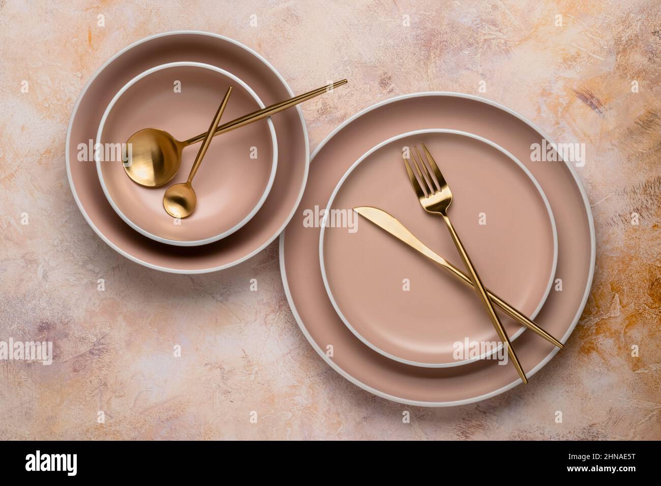 Sammlung von runden beigen Tellern in verschiedenen Größen auf dem Tisch, Draufsicht. Goldenes Besteck und Geschirr zum Servieren und Essen. Modernes Handwerk Keramik t Stockfoto