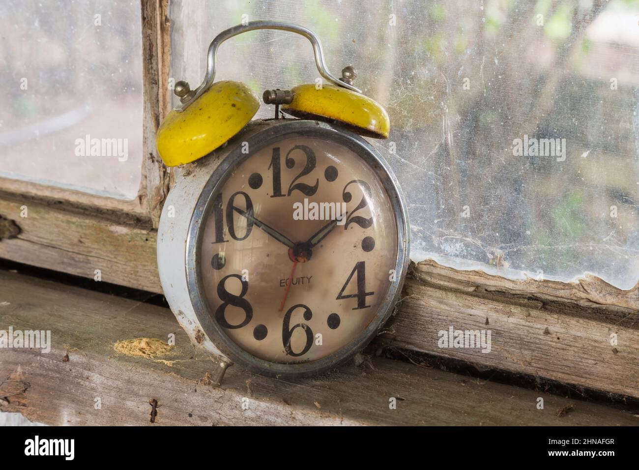 Mechanischer Wecker der Marke Antique Equity auf der Fensterbank in der alten rustikalen Holzdiele-Kabine. Stockfoto