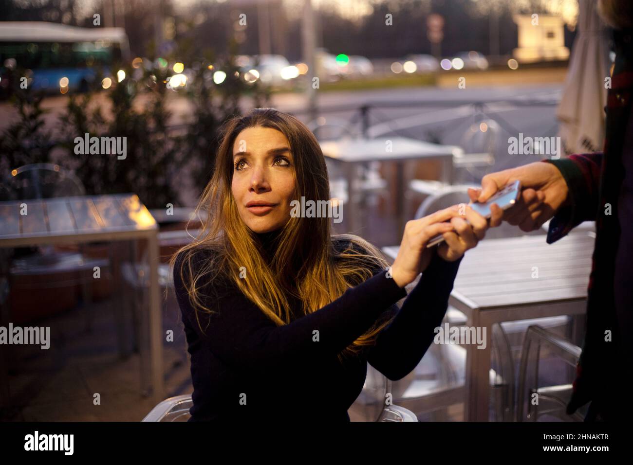 Mann greift in einem Café schlecht auf das Handy seines Partners Stockfoto