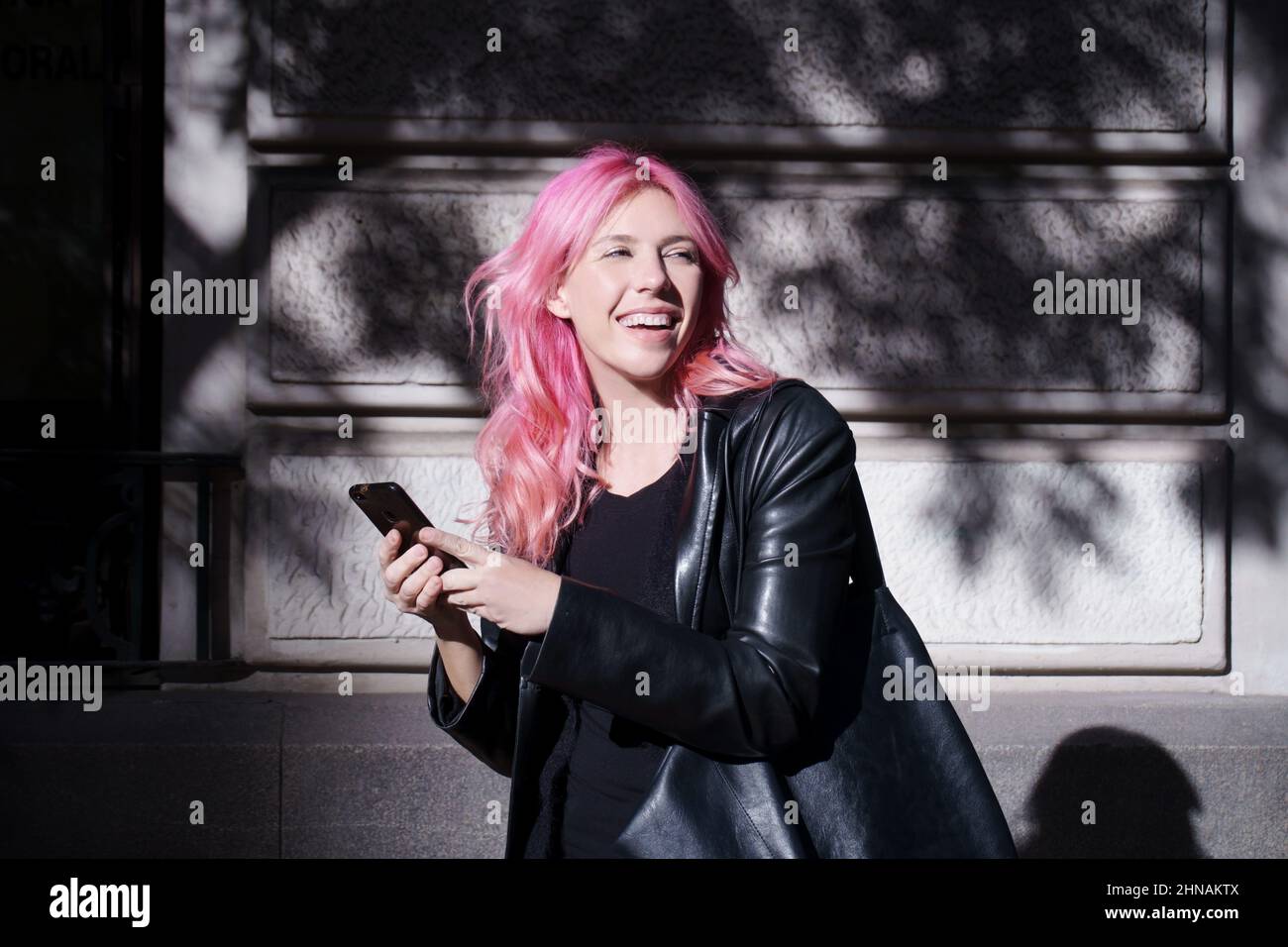 Glückliches Mädchen im Rocker-Look mit Handy in der Hand im Freien Stockfoto