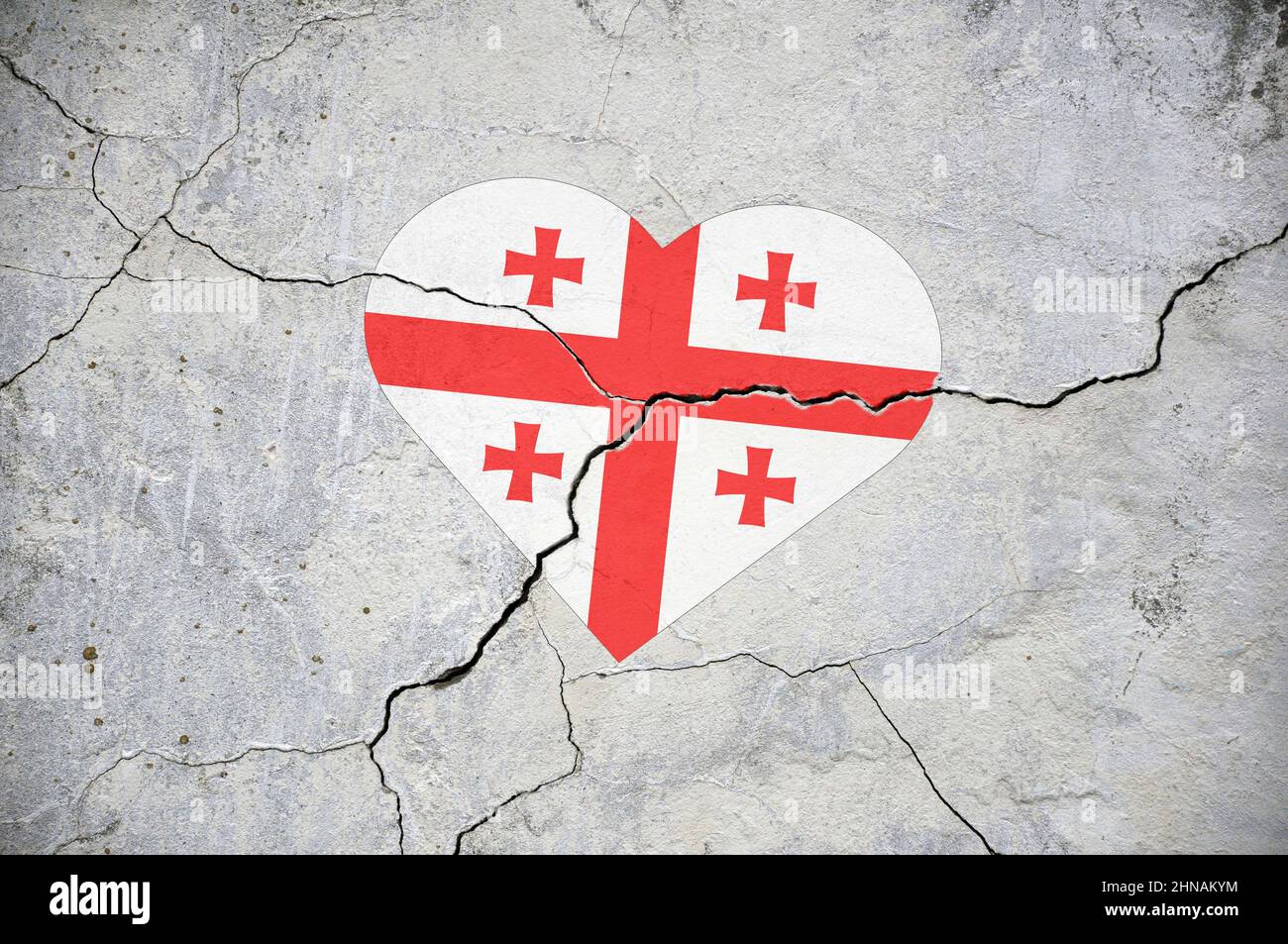 Das Symbol der Nationalflagge Georgiens in Form eines Herzens auf einer rissigen Betonwand. Konzept. Stockfoto