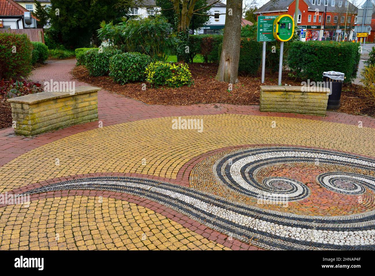 Öffentlicher Platz mit Mosaikpflaster und öffentlichem Defibrillator Hartley Wintney, Hampshire, Großbritannien Stockfoto