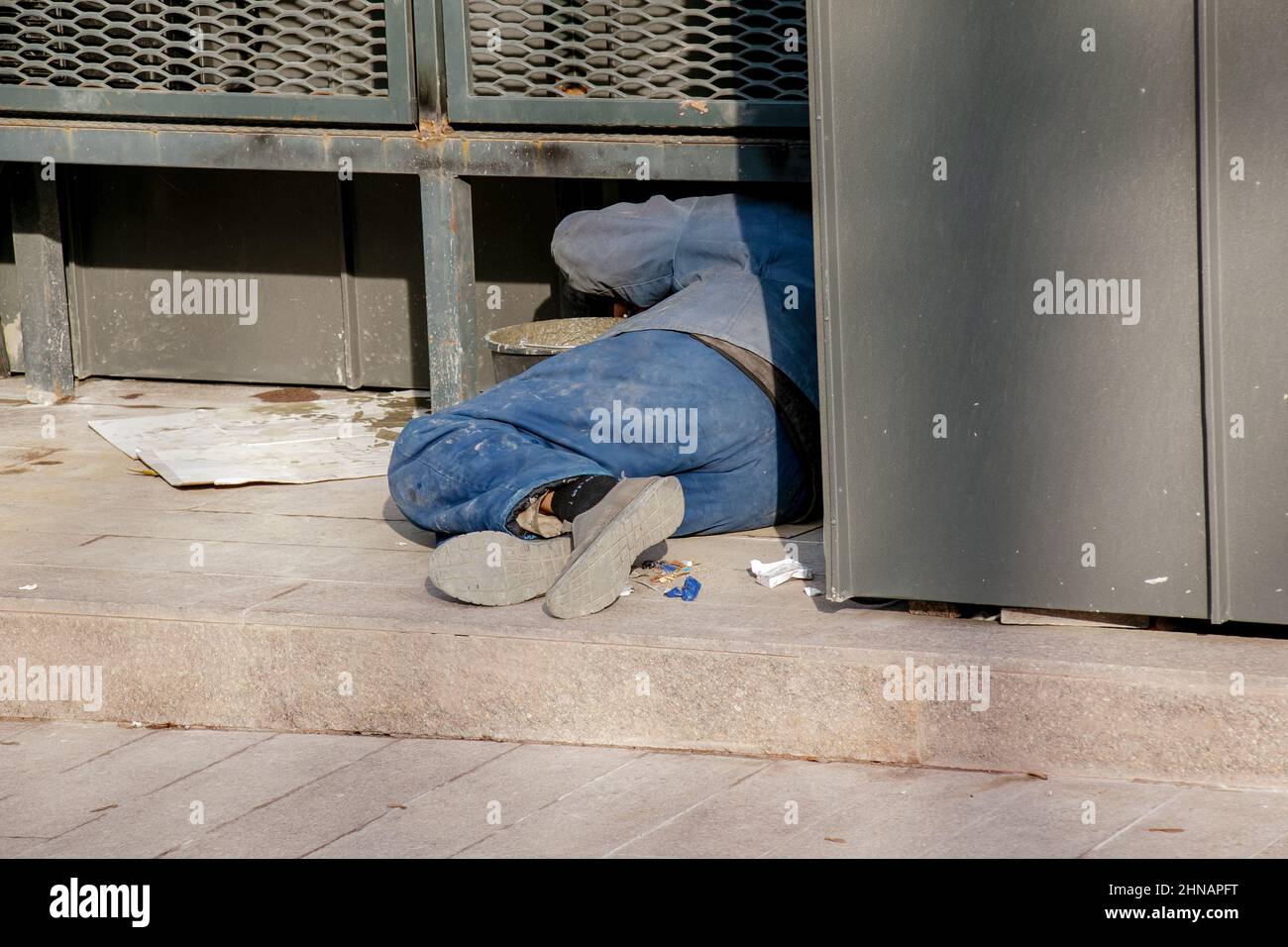 Ein Obdachloser schläft draußen im Schatten eines Gebäudes. Stockfoto