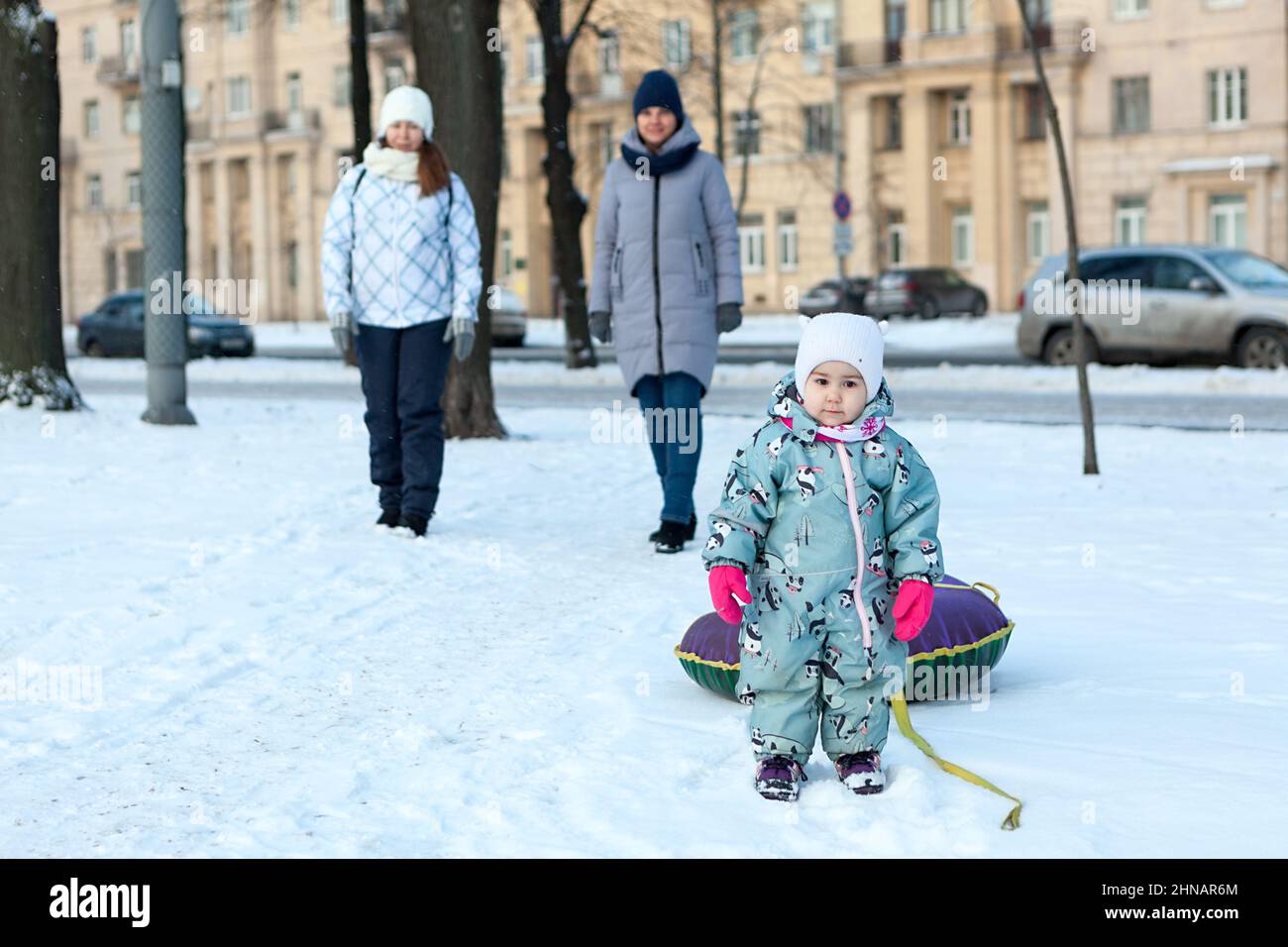 Zwei junge kaukasische Frauen mit einem kleinen Kind, die in der Wintersaison mit dem Schlauch spazieren gehen Stockfoto