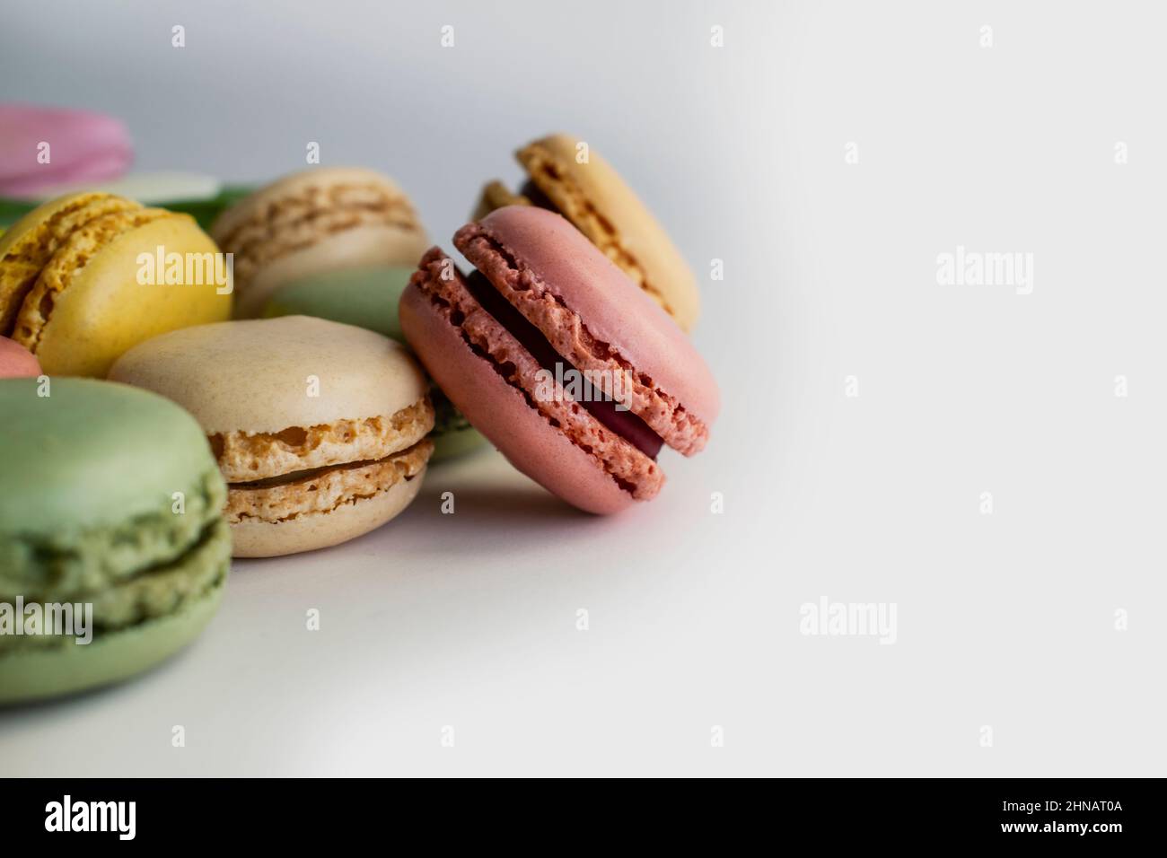 französische Kuchenmakronen und Frühlingsblumen auf weißem Hintergrund Stockfoto