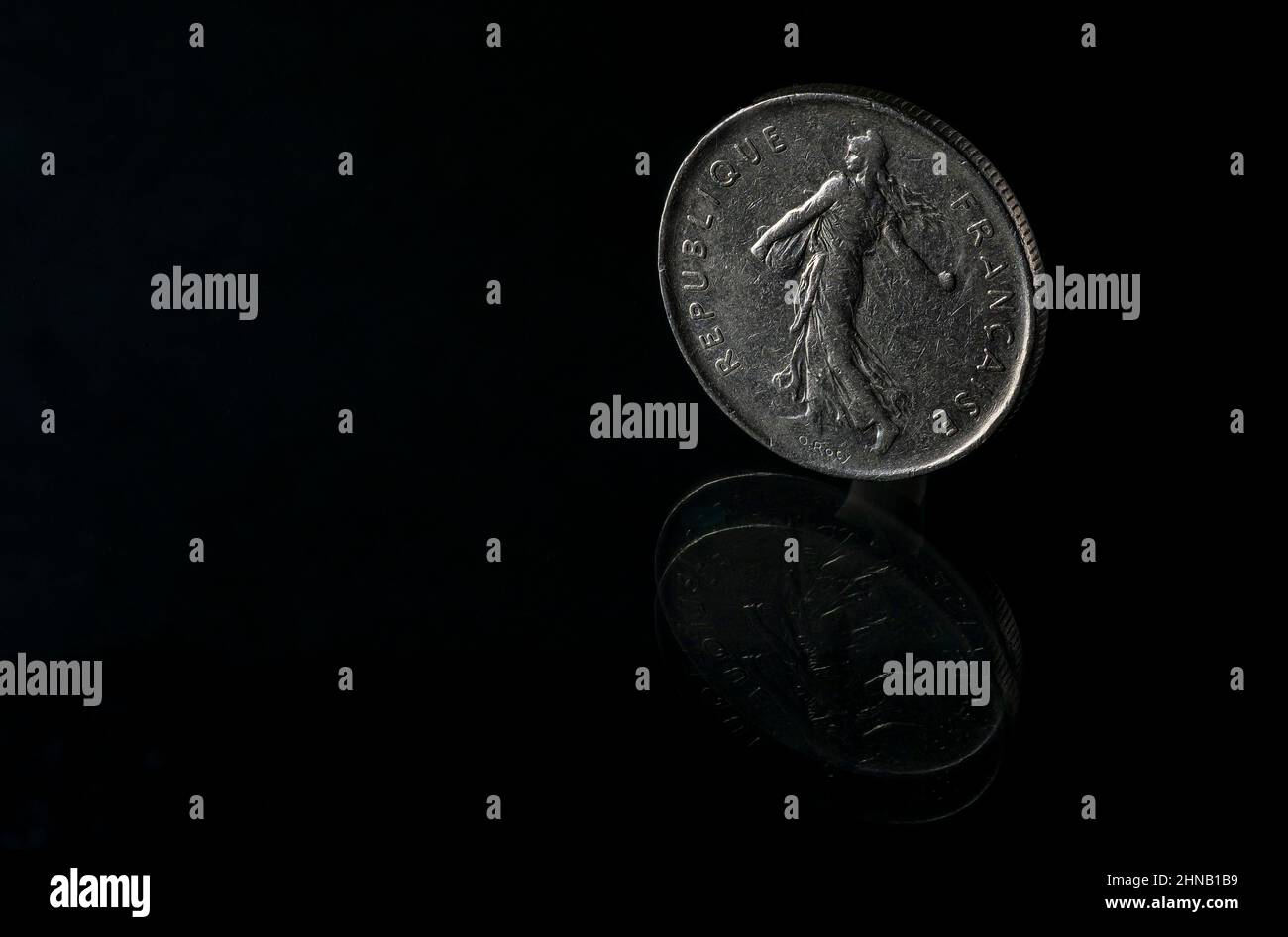 Französische Münze 5 Francs stehend auf reflektierender Oberfläche negativer Raum schwarzer Hintergrund Stockfoto