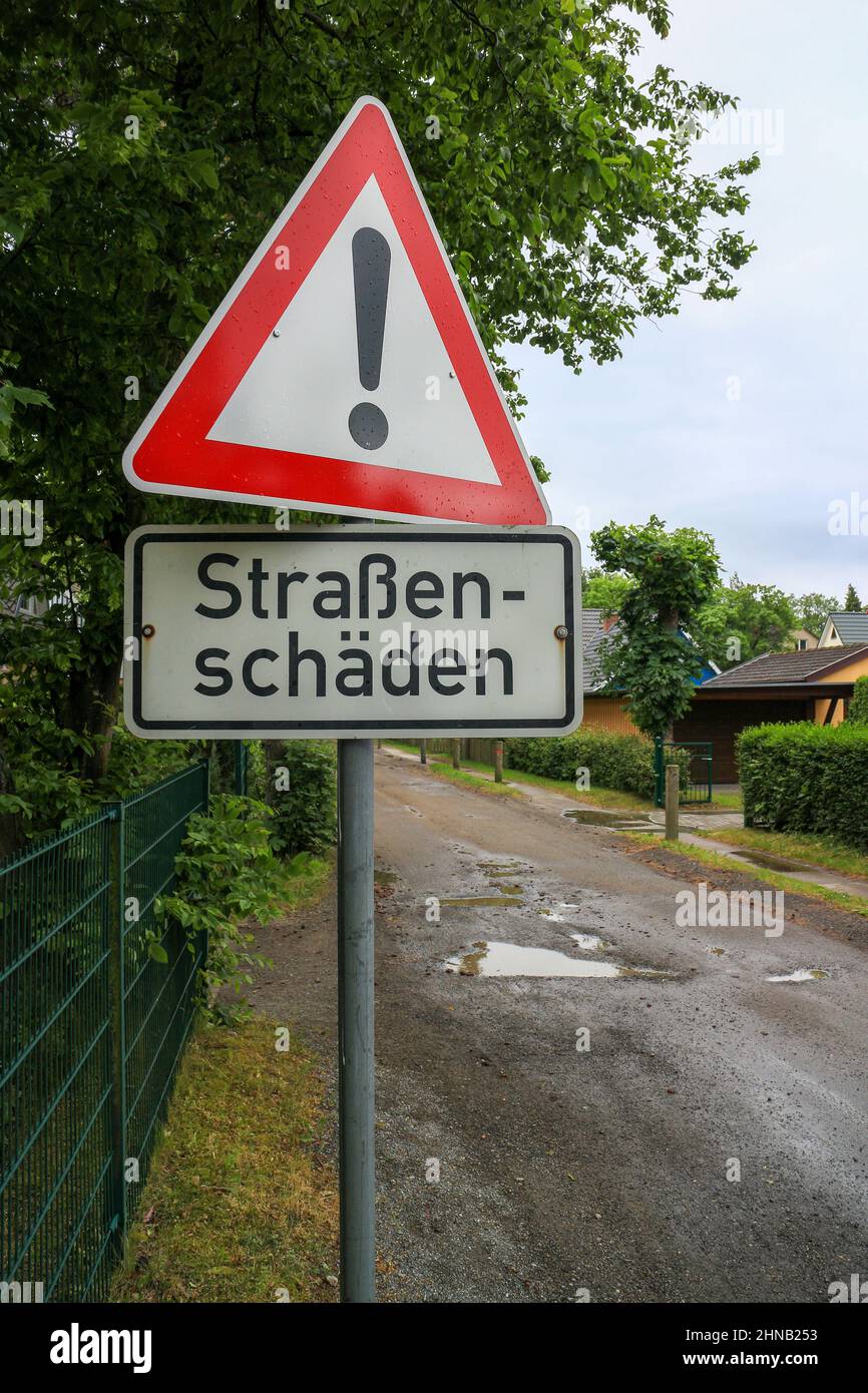 Warnschild mit dem deutschen Text „Straßenschäden“, der in englischer Sprache in „Straßenschäden“ übersetzt wird Stockfoto