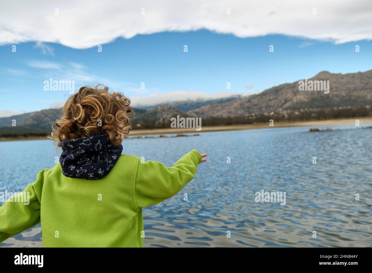 Rückansicht eines Kindes, das Steine in einen See wirft. Stockfoto