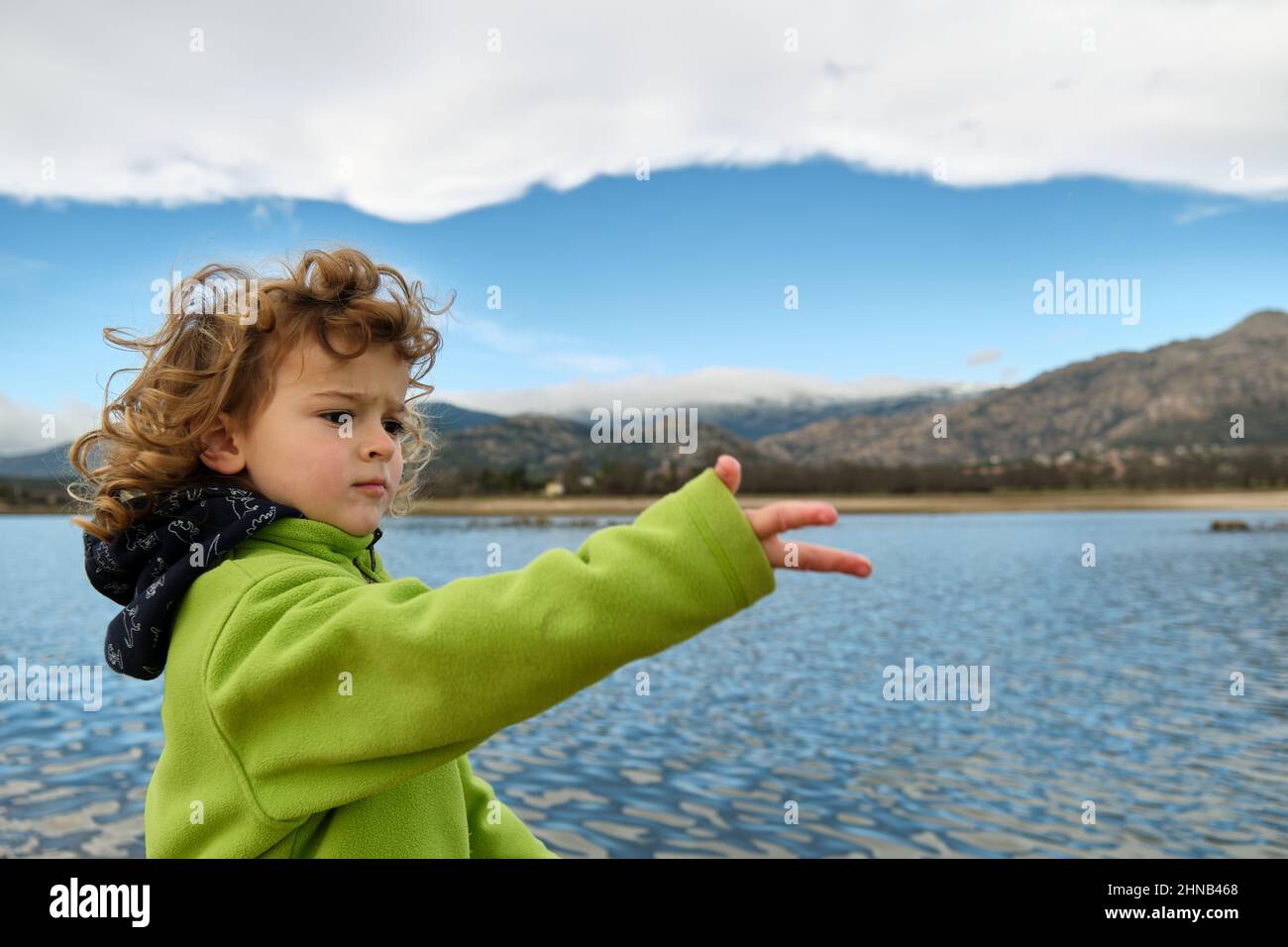 Porträt eines Kindes, das dabei spielt, Steine ins Wasser zu werfen Stockfoto