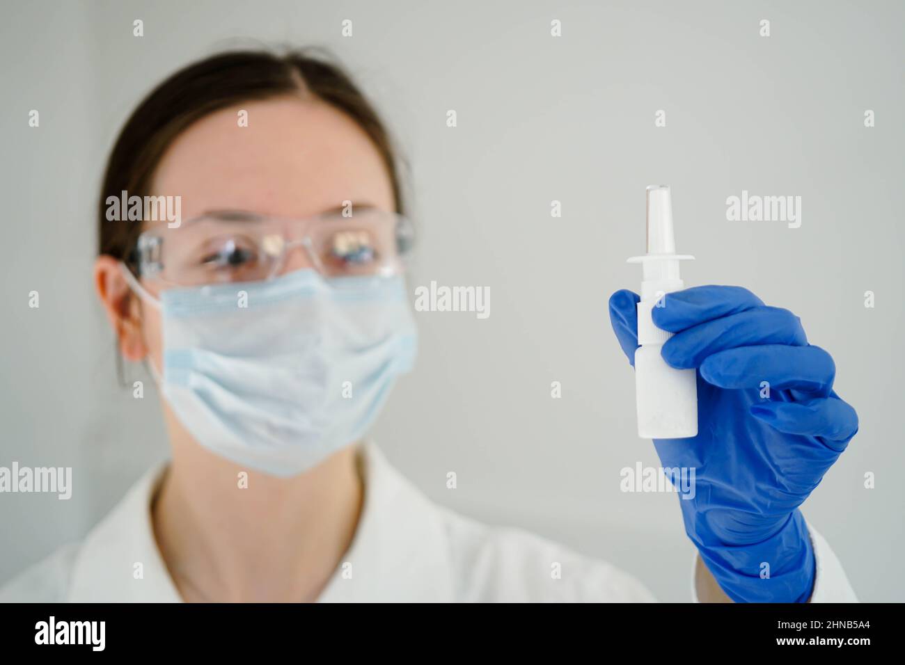 Weibliche medizinische Forscherin in Handschuhen mit einem weißen Nasenspray. Nahaufnahme. Stockfoto