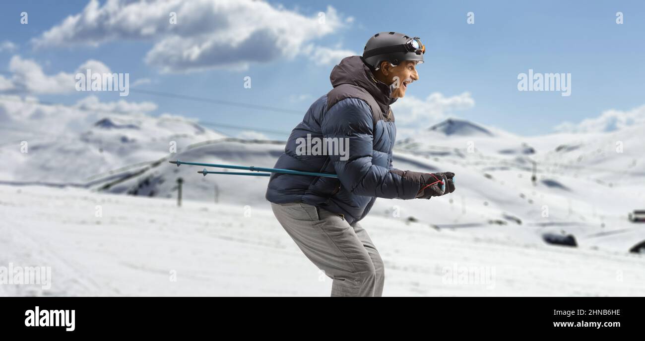 Profilaufnahme eines reifen Mannes, der auf einem Berg Ski fährt Stockfoto