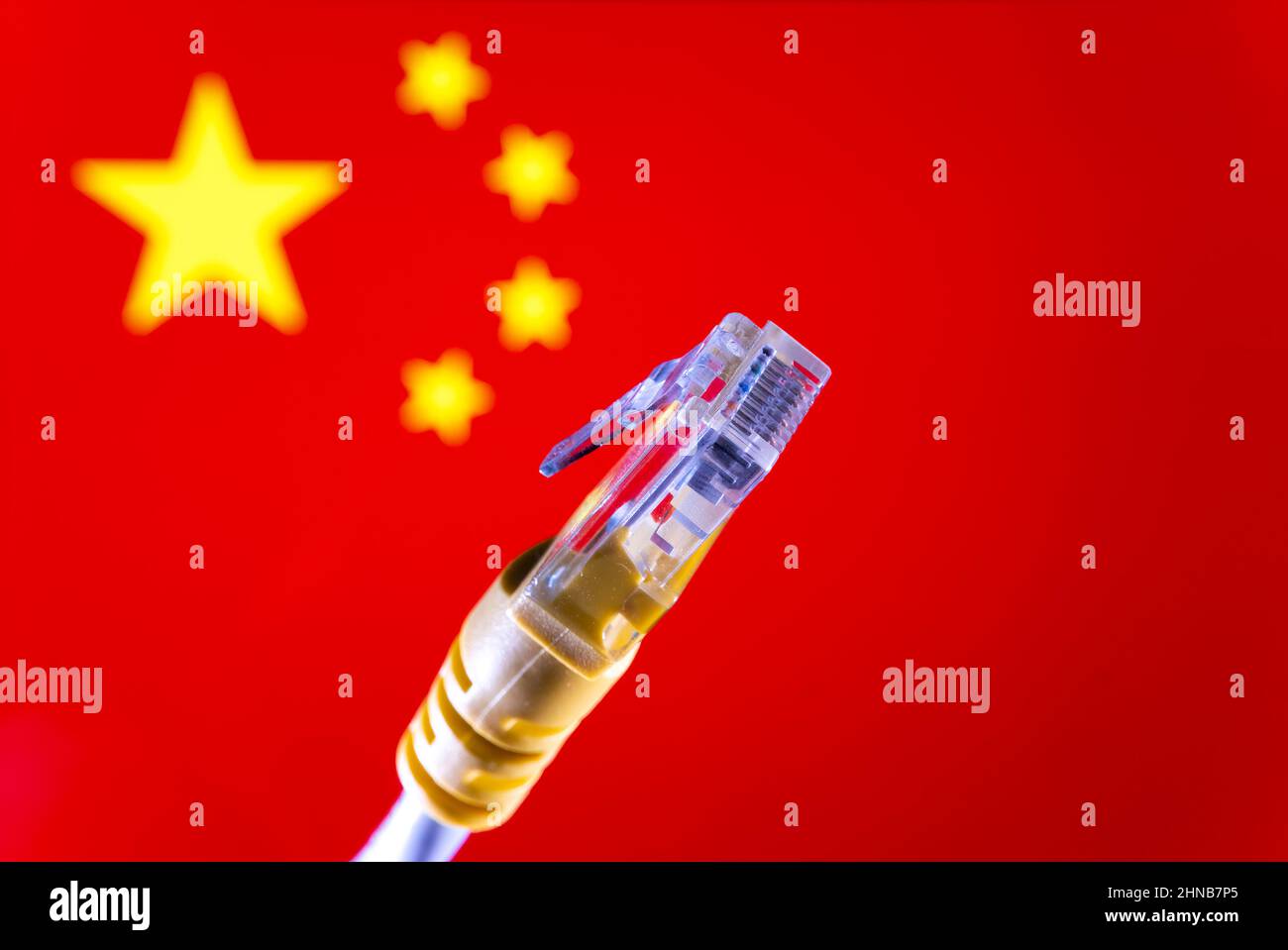 Internet in China Konzept. Ethernet-Kabelanschluss und verschwommene chinesische Flagge auf dem Hintergrund. Selektiver Fokus. Stockfoto