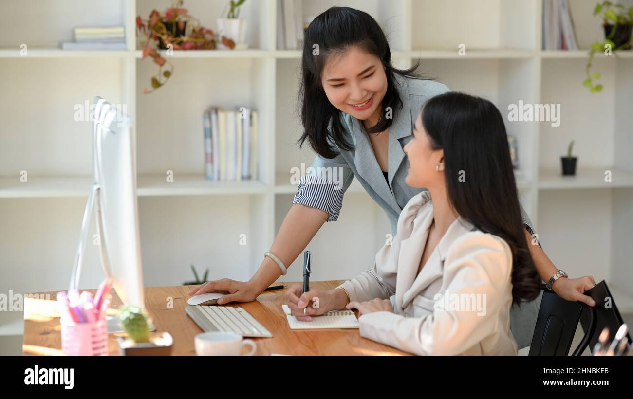 Freundliche Managerin, die ihre junge Marketingassistentin im Büro freundlich berät Stockfoto