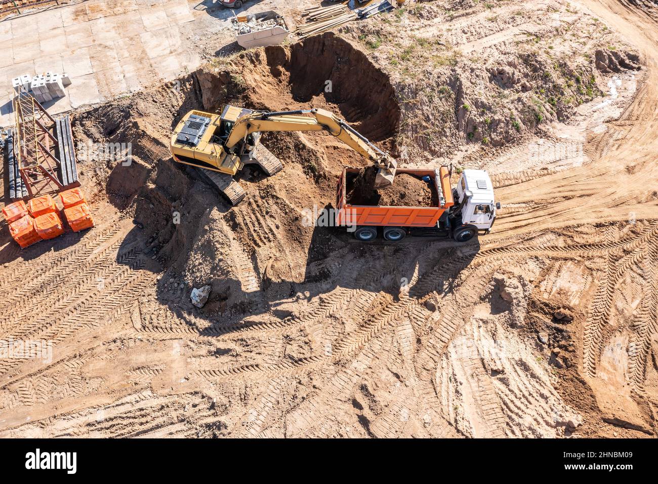 Lader Bagger belädt den Boden im LKW auf der Baustelle. Luftaufnahme von oben. Stockfoto