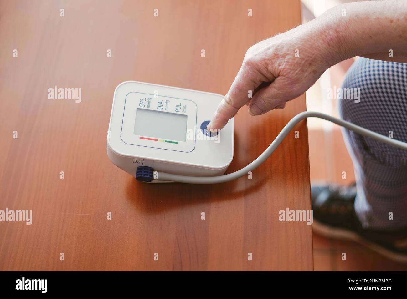 Die alte Frau drückt mit ihrem Finger die Starttaste eines Blutdruckmessschalters Stockfoto