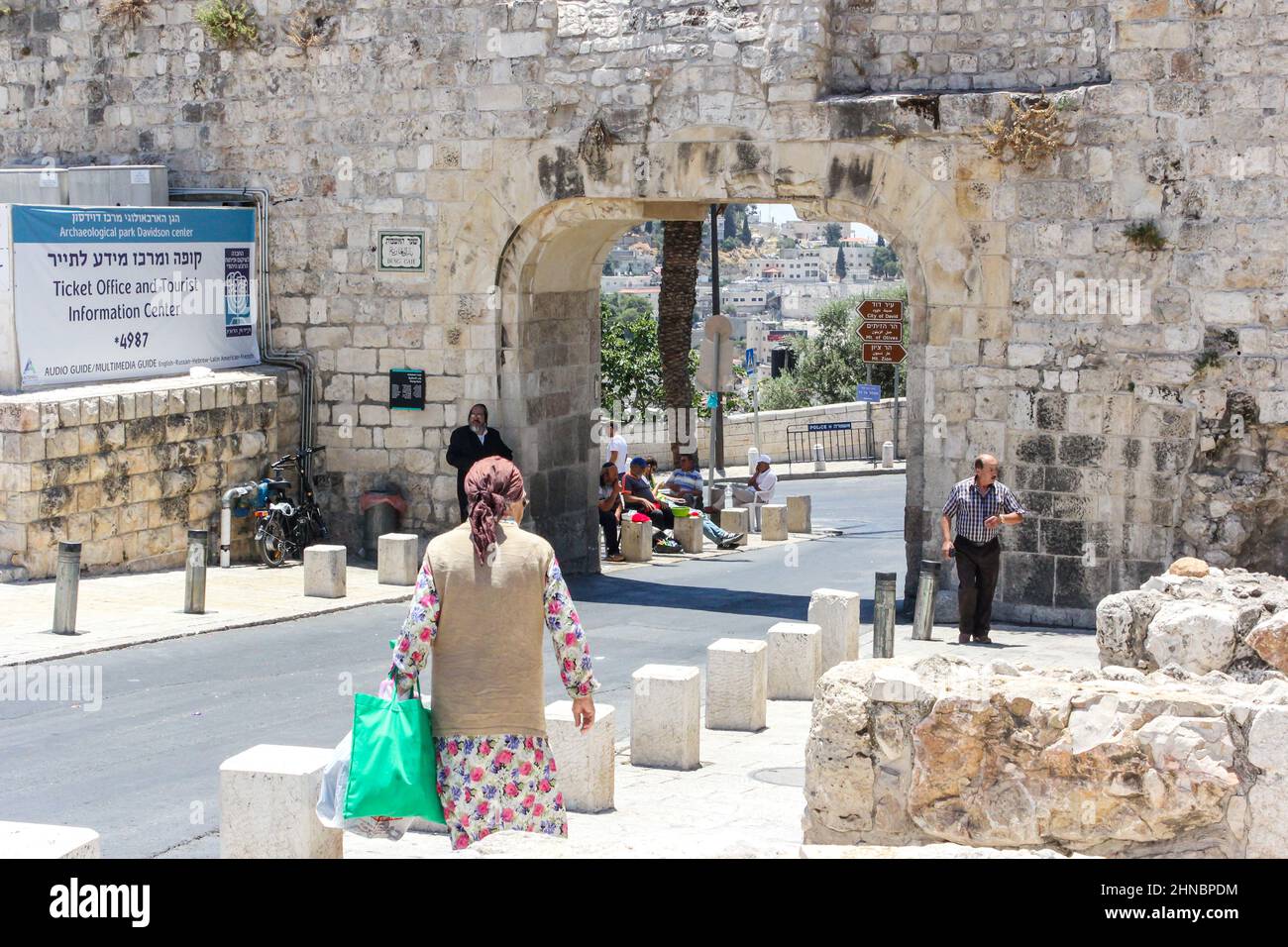 Eine Frau mit einer Tasche nähert sich den historischen Mauern der Altstadt von Jerusalem an der Batei Mahase Street am Dung Gate, auch bekannt als Silwan oder Mughrabi Gate. Stockfoto