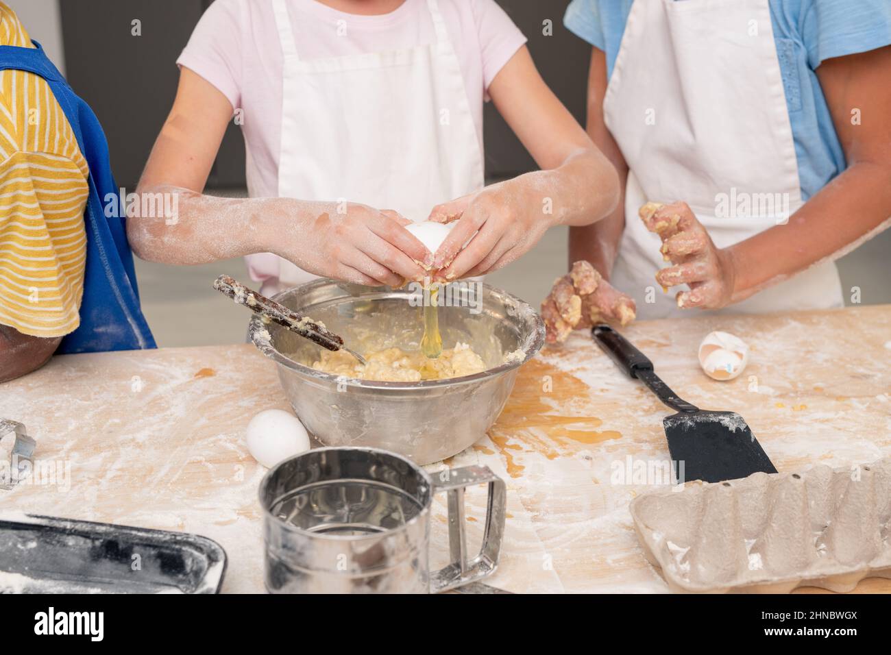 Die Kinder versammelten sich in der modernen Küche und studierten das Rezept für köstliche Desserts, während sie über ein festliches Menü für den Muttertag nachdachten Stockfoto