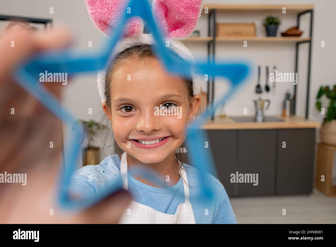 Hände von Mädchen schneiden Cookies aus gerolltem Teig beim Kochen Gebäck für Weihnachten Abendessen Stockfoto