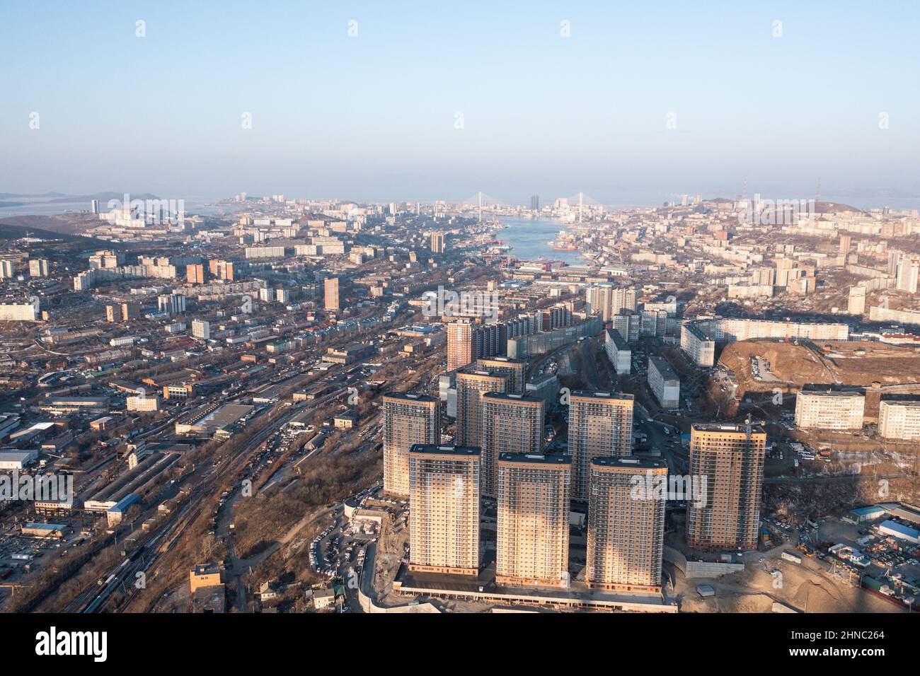Wladiwostok, Russland - 5. Februar 2022:Blick von oben auf die Häuser und Straßen der Stadt. Am Horizont können Sie das Meer und die Brücken sehen. Stockfoto
