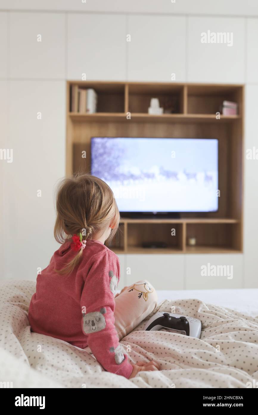 Kleines nettes Mädchen, das zu Hause Fernsehen schaut. Stockfoto