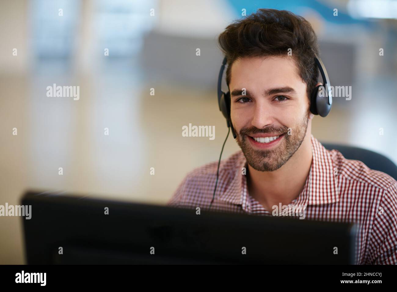 Um Ihr Geschäft zu verbessern, sollten Sie sich zunächst selbst verbessern. Aufnahme eines freundlichen, jungen Callcenter-Agenten, der an seinem Schreibtisch saß. Stockfoto