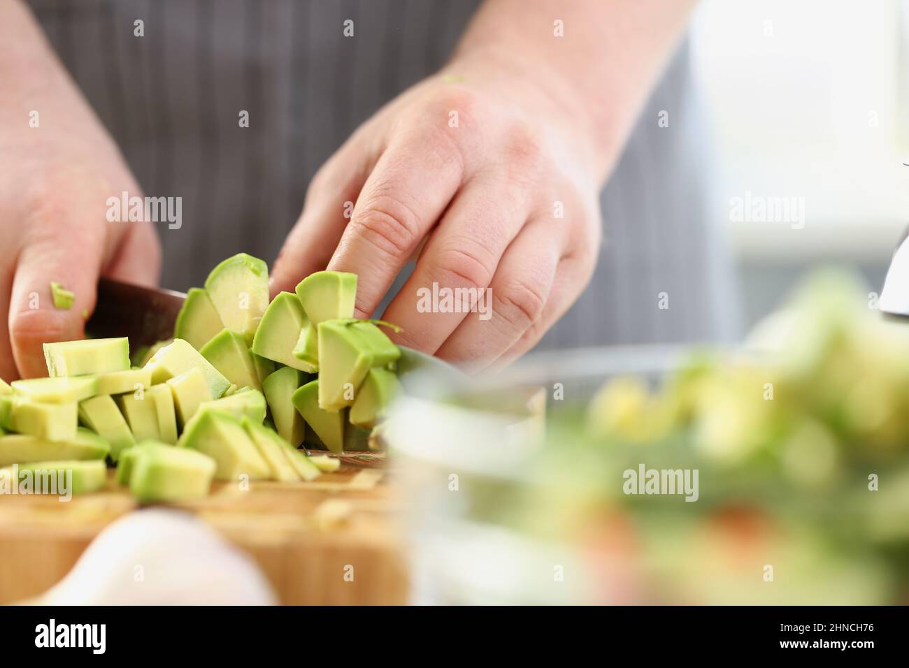 Mann schneidet sanfte Avocado auf Schneidebrett, Inspiration, um leckeres Abendessen zu kochen Stockfoto