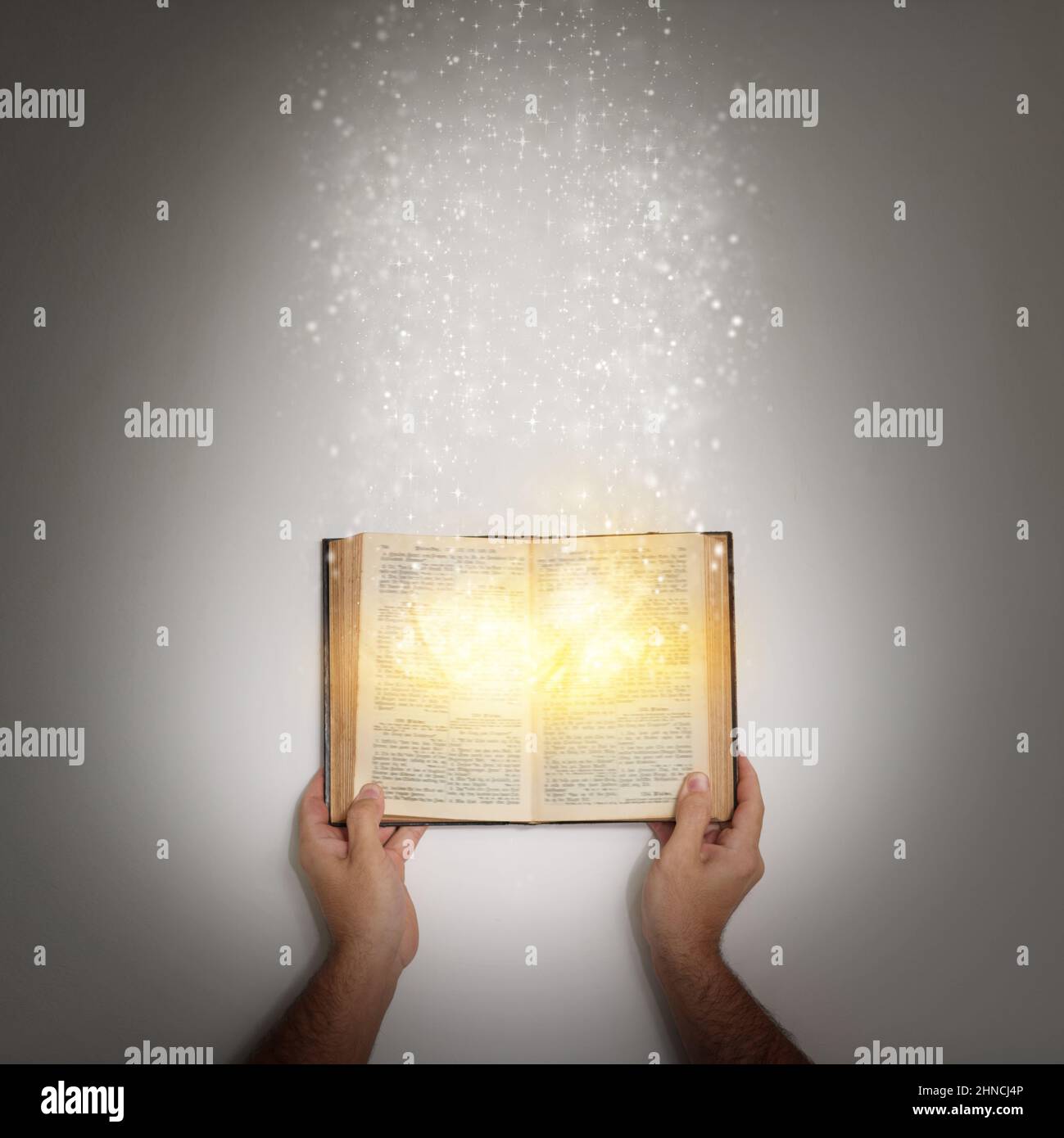 Du bist nie zu alt für ein Märchen. Aufnahme einer Hand, die ein offenes Märchenbuch mit Licht hält, das von ihm ausgeht. Stockfoto