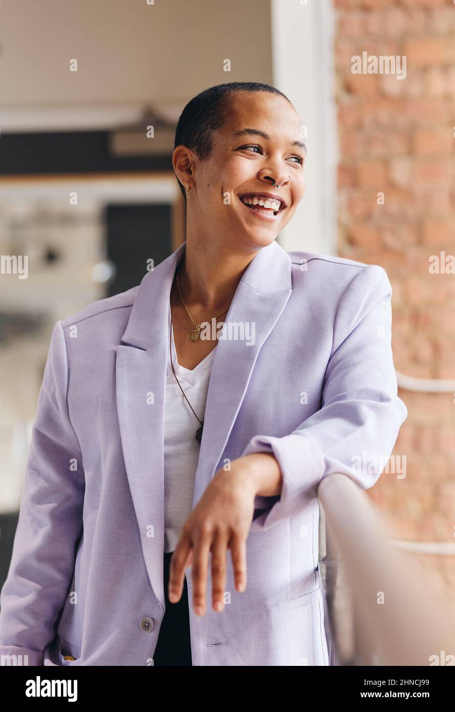 Porträt einer selbstbewussten, multirassischen LGBTQ-Frau mit mittlerem Erwachsenen, die lächelt und im Büro wegschaut Stockfoto