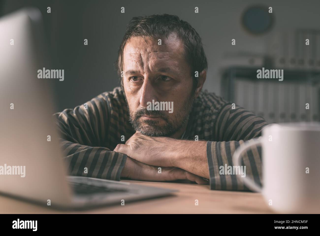 Lethargischer Mitarbeiter, der spät in der Nacht auf den Bildschirm eines Laptop-Computers im Büro schaut, selektiver Fokus Stockfoto