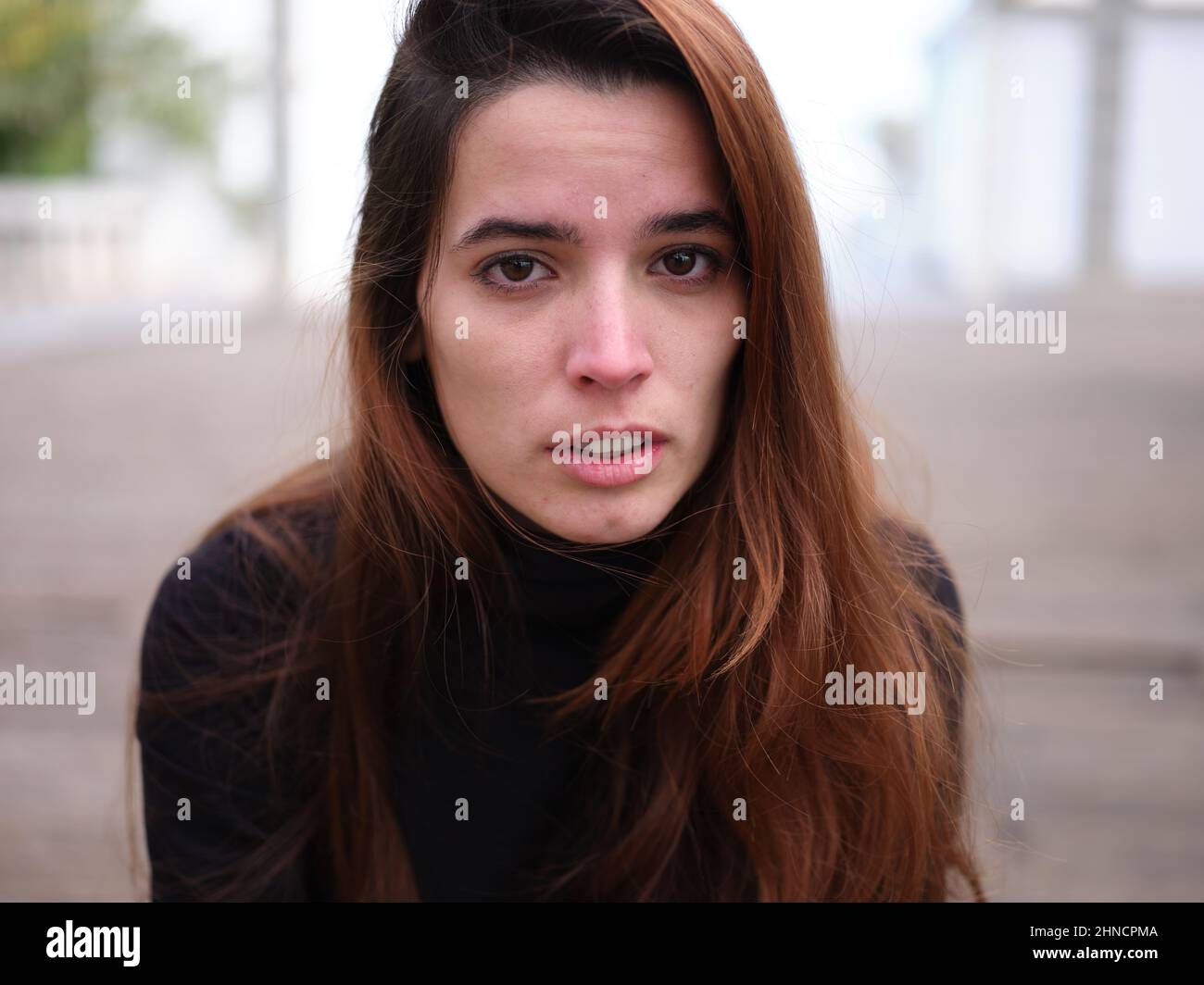 Ein trauriges junges Mädchen, das die Kamera ansieht, weint vor unfokussierter Kulisse. Stockfoto