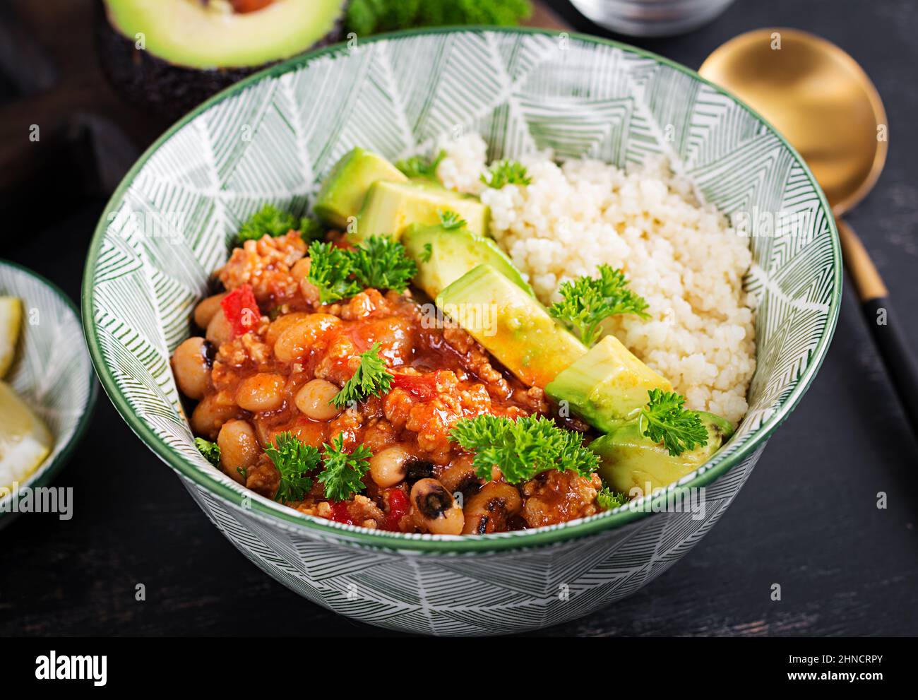 Chili con Carne und Couscous in einer Schüssel auf dunklem Hintergrund. Mexikanische Küche. Stockfoto