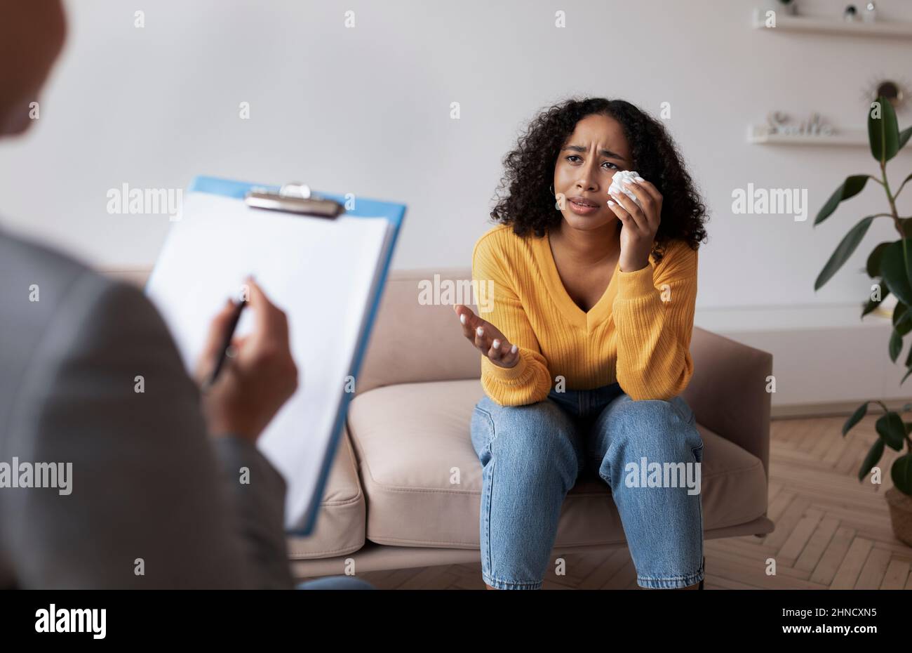 Junge afroamerikanische Frau weint während der Sitzung mit einem Psychologen und spricht mit einem Psychologen im Büro Stockfoto