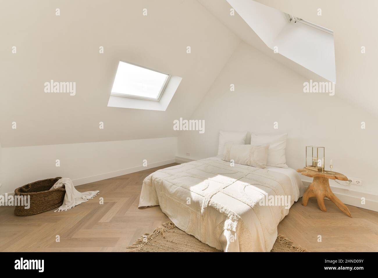 Interieur des Schlafzimmers im rustikalen Stil mit komfortablem Bett mit Kissen und Decke neben Nachttisch und Korbkorb Stockfoto