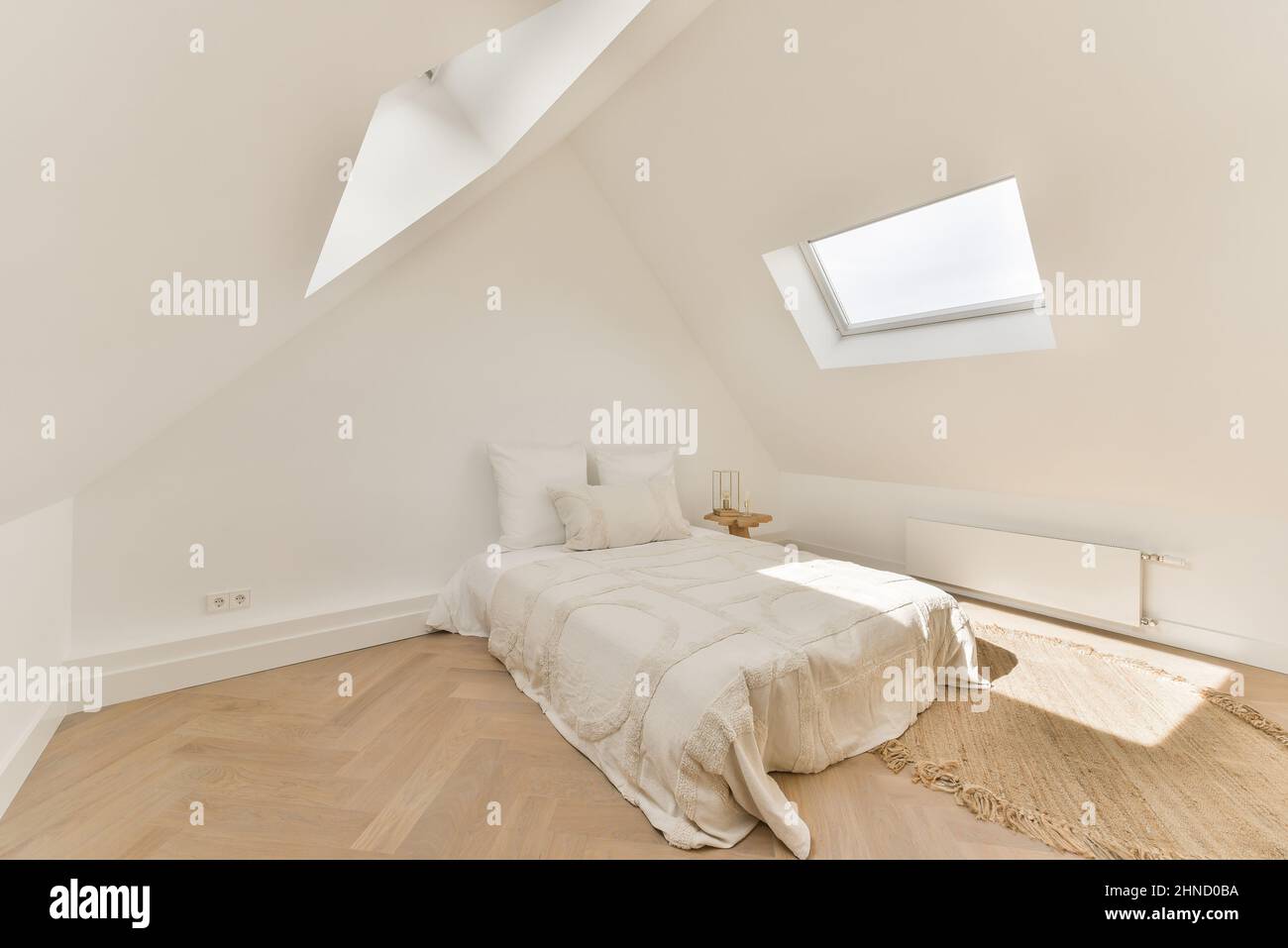 Interieur des Schlafzimmers im rustikalen Stil mit komfortablem Bett mit Kissen und Decke neben Nachttisch und Korbkorb Stockfoto