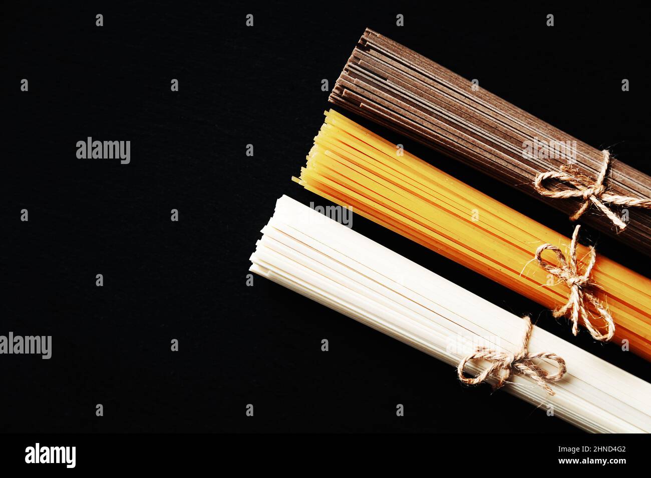 Nudeln aus verschiedenen Ländern. Soba, udon, Spaghetti. Schwarzer Hintergrund, flaches Lay, Kopierbereich. Hintergrund der Speisen. Stockfoto