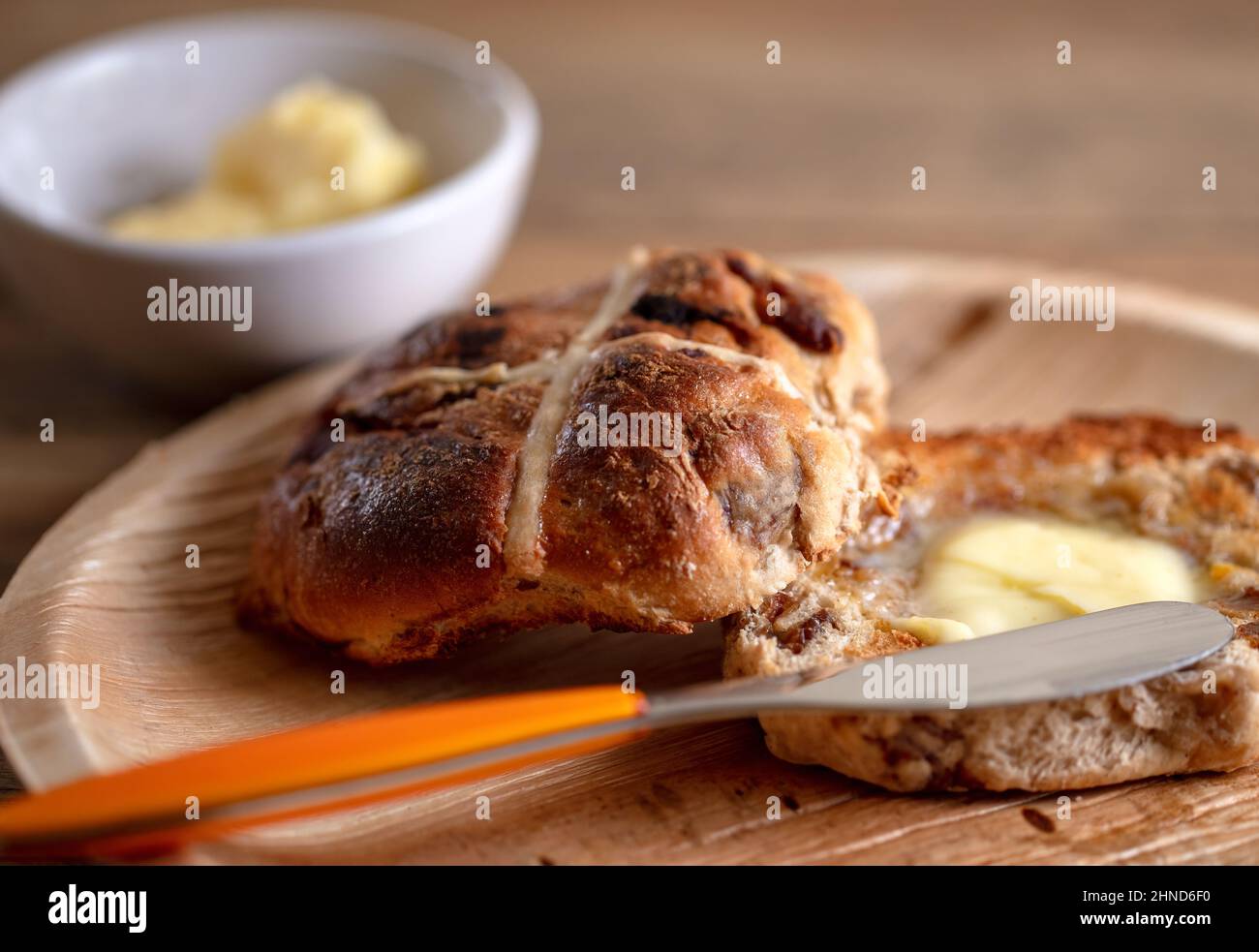 Ein geröstetes und gebuttertes Hot Cross Bun, ein süßes gewürztes Bun, das traditionell am Karfreitag gegessen wird Stockfoto