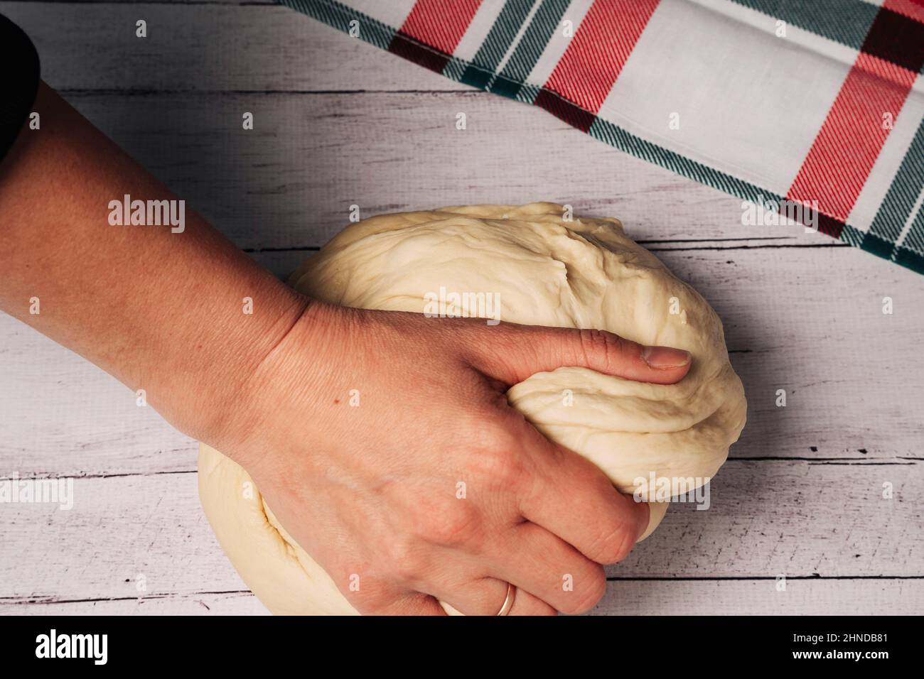 Die Hände des Küchenchefs bereiten frischen hausgemachten Pizzateig auf dem Küchentisch zu und kneten, schöne weibliche Hände kneten den Teig, machen Brot, Pasta oder Pizza Stockfoto