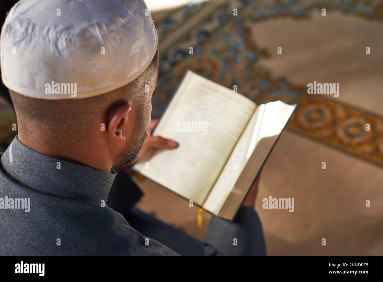 Über der Schulter eines jungen muslimischen Mannes, der den Koran liest Stockfoto