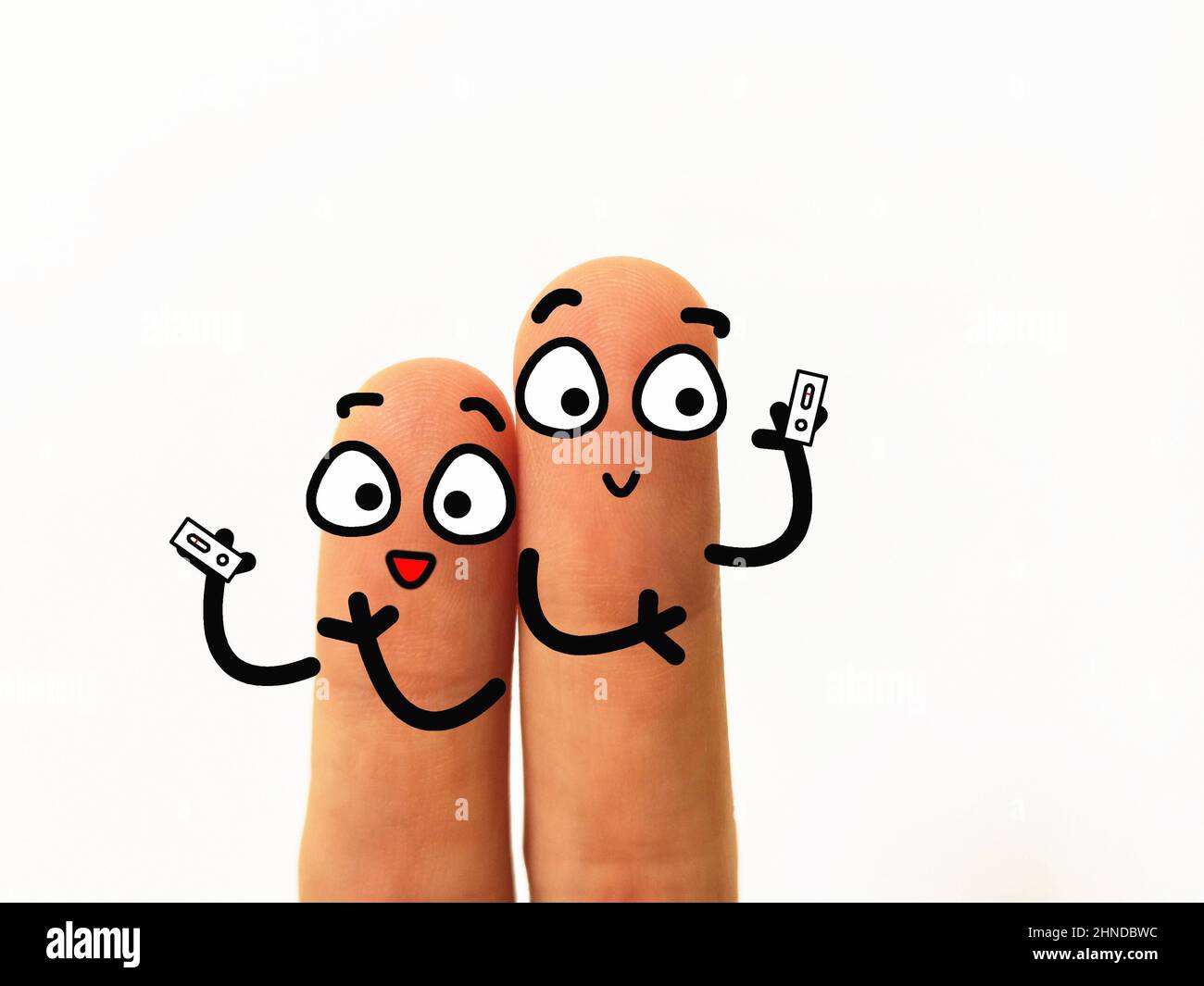 Zwei Finger sind als zwei Personen dekoriert. Sie verwenden Coronavirus-Schnelltestkit. Sie sind glücklich. Stockfoto