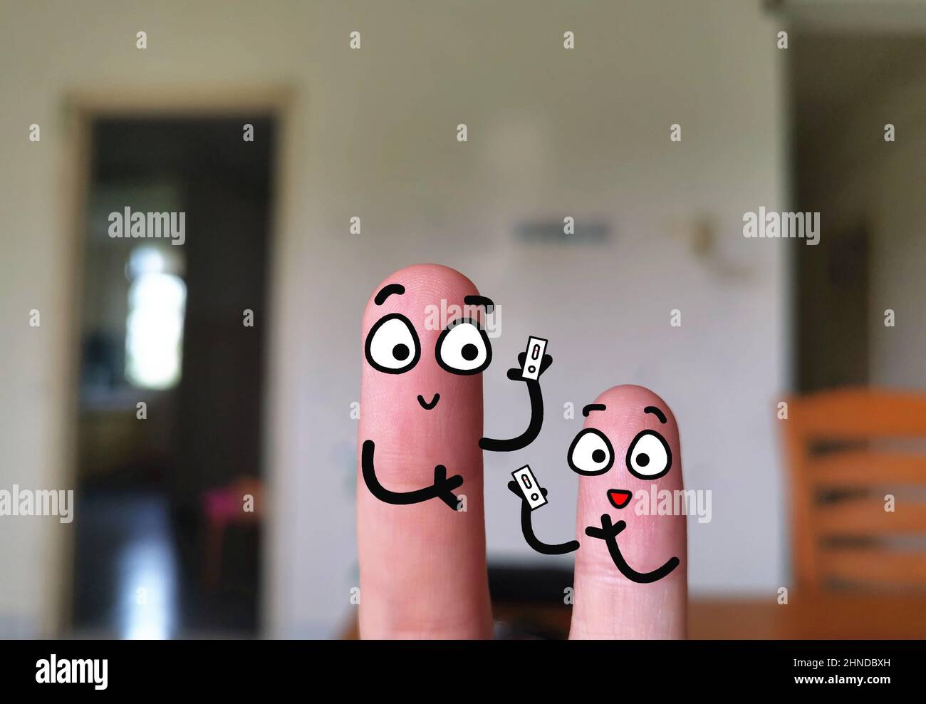 Zwei Finger sind als Mutter und Sohn geschmückt. Sie verwenden Coronavirus-Schnelltestkit. Stockfoto