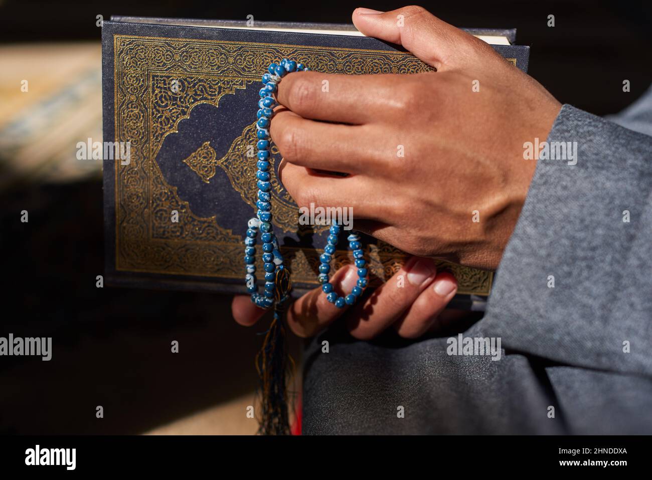 Nahaufnahme der Hände eines muslimischen Mannes, der islamische Gebetsperlen und den Koran hält Stockfoto