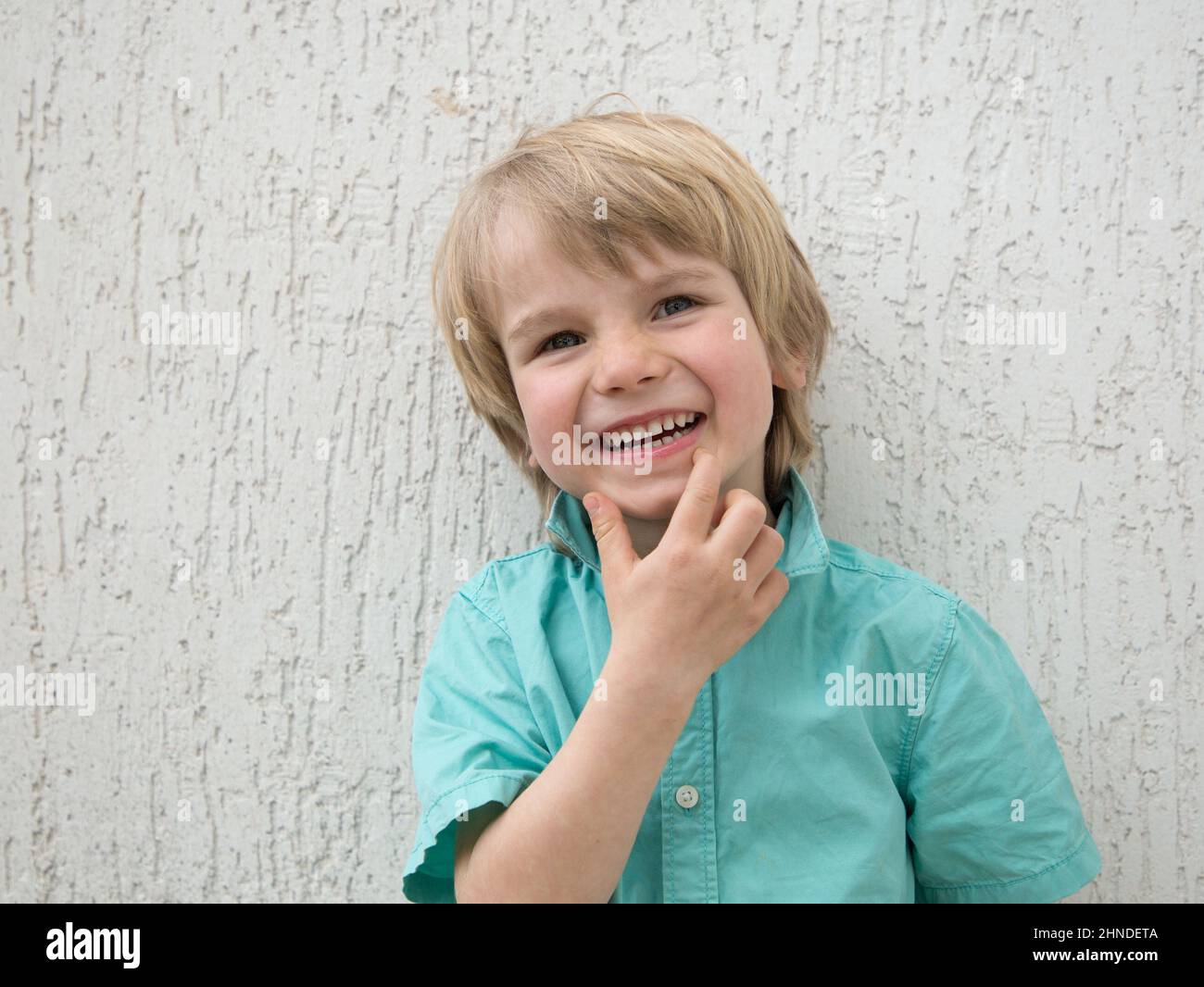 Porträt eines charmanten Kindes in einem Hemd mit einem niedlichen Lächeln. Gute Laune, positive Einstellung, fröhliche Kindheit. Porträt eines Vorschulkinder mit einem Interesse Stockfoto