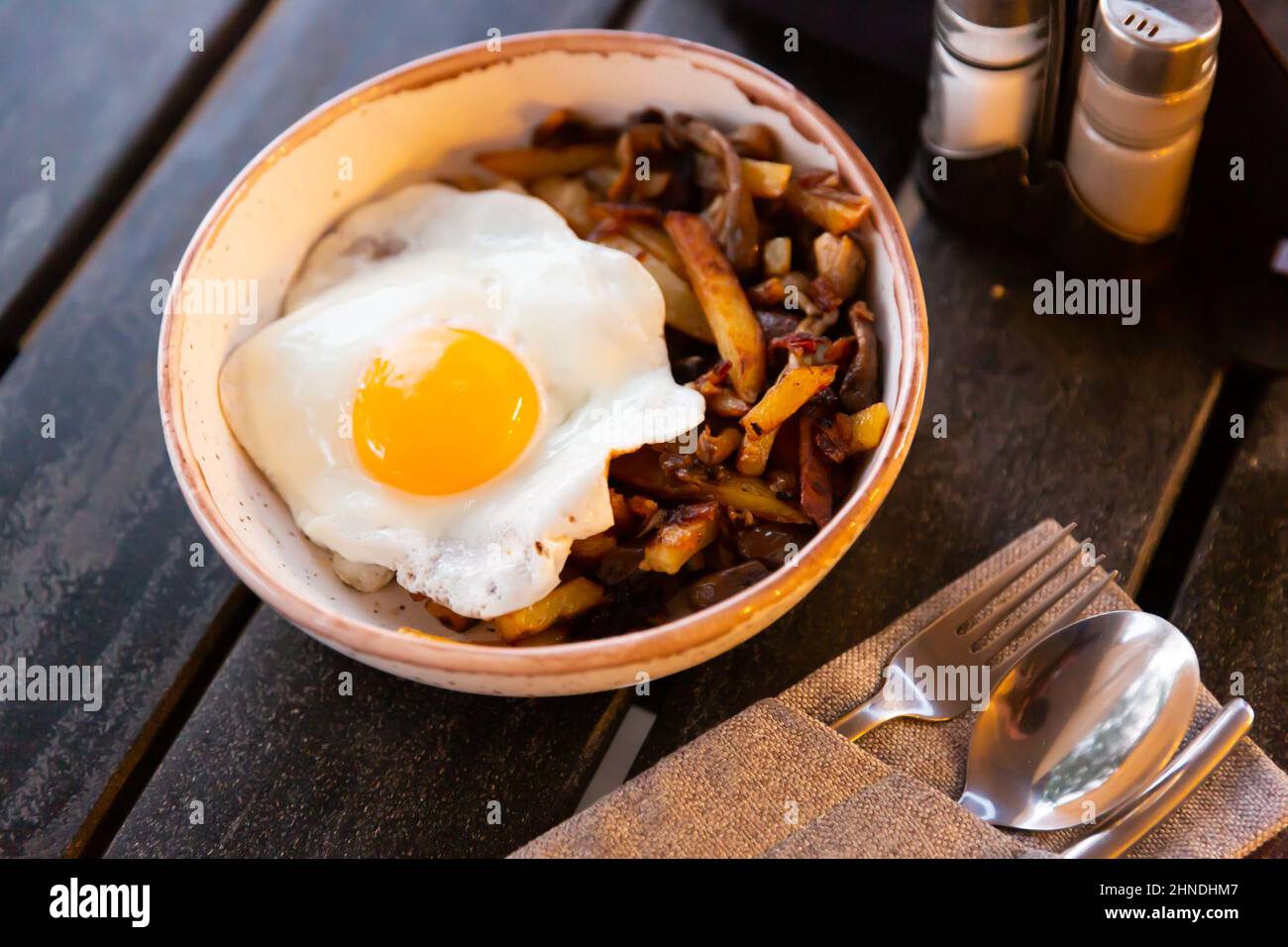 Gebratene Kartoffeln mit Zwiebeln, Pilzen und Ei in der sonnigen Seite Stockfoto